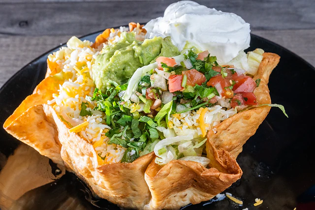 Tostada compuesta topped with guacamole and sour cream