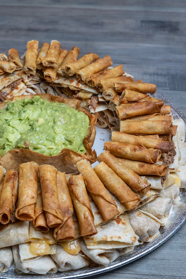Party tray of mini taquitos, burritos and quesadillas with guacamole