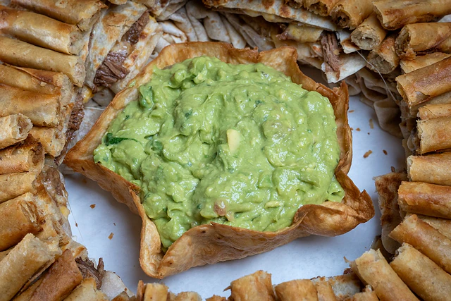 Guacamole surrounded by mini taquitos