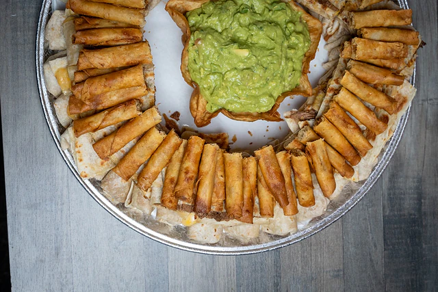 Party tray of mini taquitos with guacamole