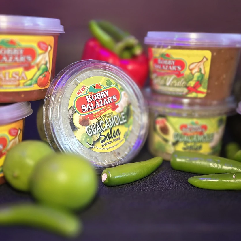 Bobby Salazar’s salsa, salsa verde and guacamole salsa tubs with limes and jalapeños